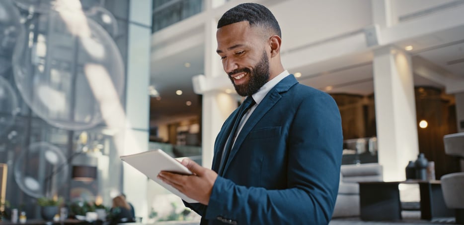 Businessman-in-suit-smiling-holding-tablet-2x